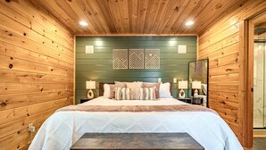 Een slaapkamer met houten lambrisering, een bed, nachtkastjes en een bankje.