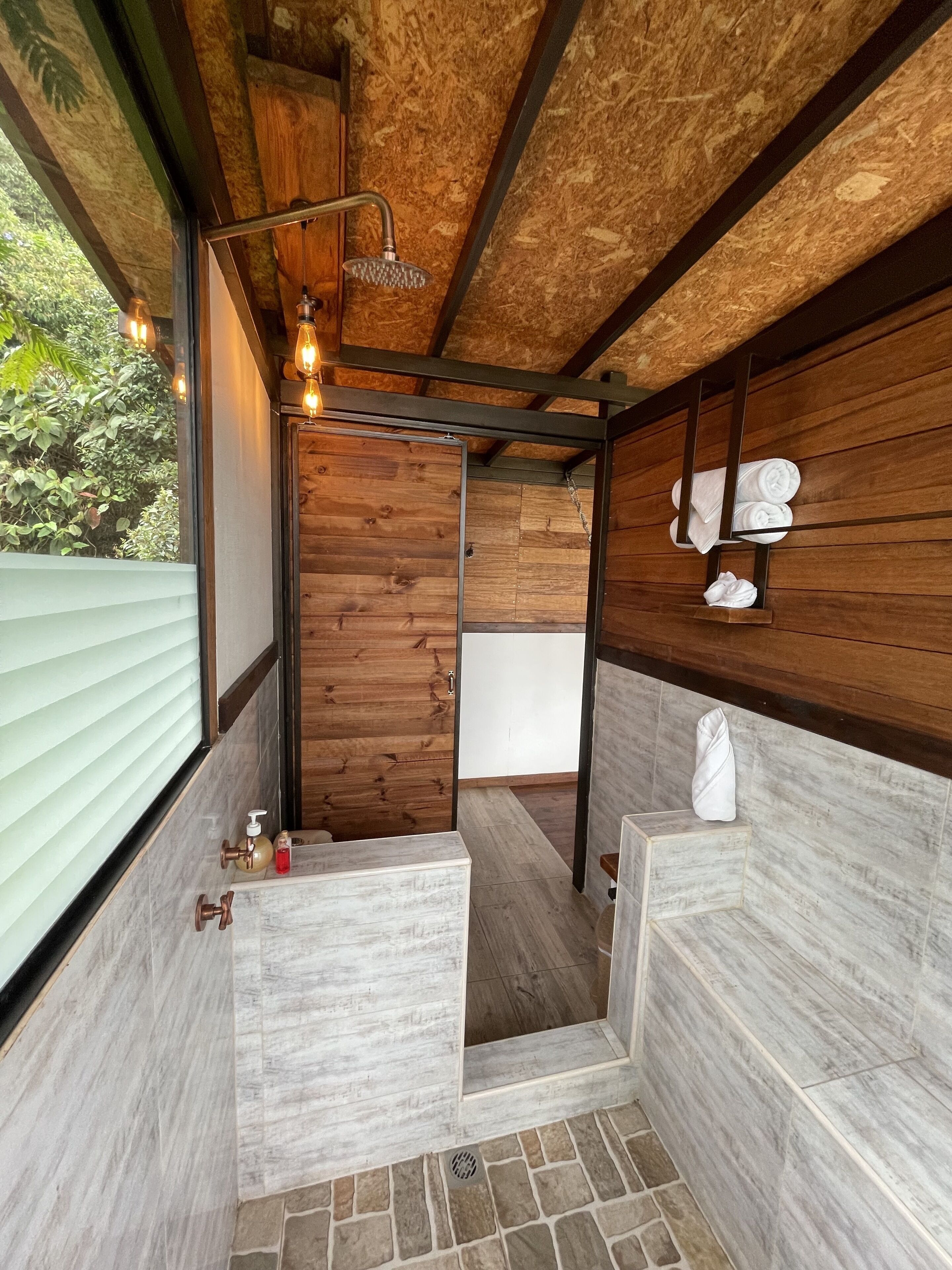 A modern bathroom with wooden walls, a shower, and a built-in bench.