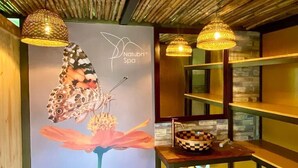 A spa area with a sign reading "Naturbri Spa", a decorative butterfly on a flower, and checkered bowls on a wooden table. - Natubri Ecohotel (San Francisco)