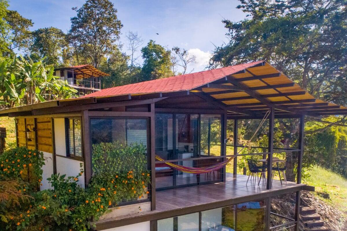 Ein modernes Haus mit einer verglasten Terrasse, einer Hängematte und Blick auf die umliegende Grünfläche.