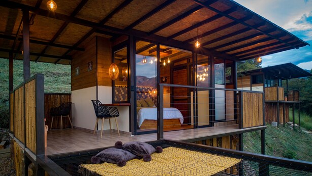 A modern cabin with a wooden deck, a bed, a desk, and a chair. - Natubri Ecohotel (San Francisco)