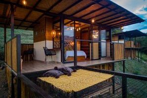 Una moderna cabina con terrazza in legno, un letto, una scrivania e una sedia.