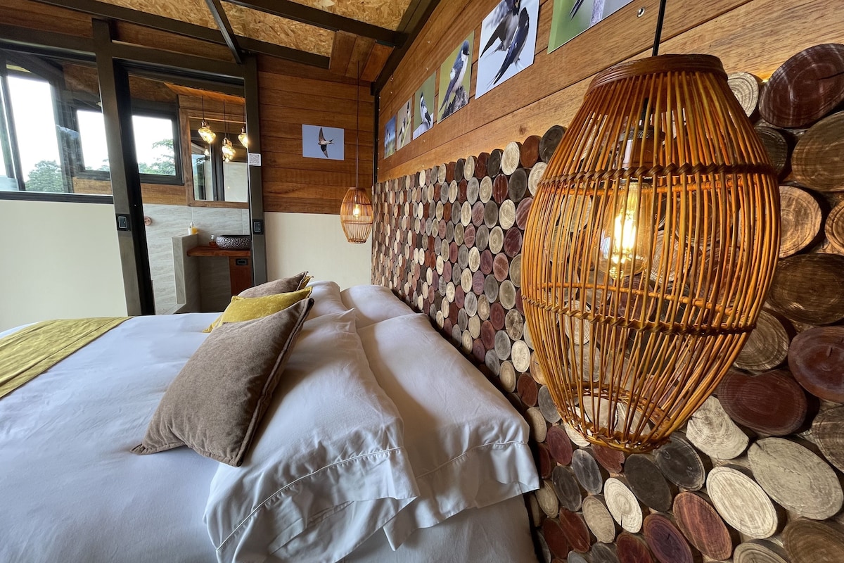 Ein Bett mit Kissen, eine Wand mit Holzbalken und eine hängende Leuchte.