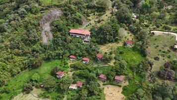 Vista aérea de uma área residencial com várias casas cercadas por vegetação densa e um penhasco imponente.