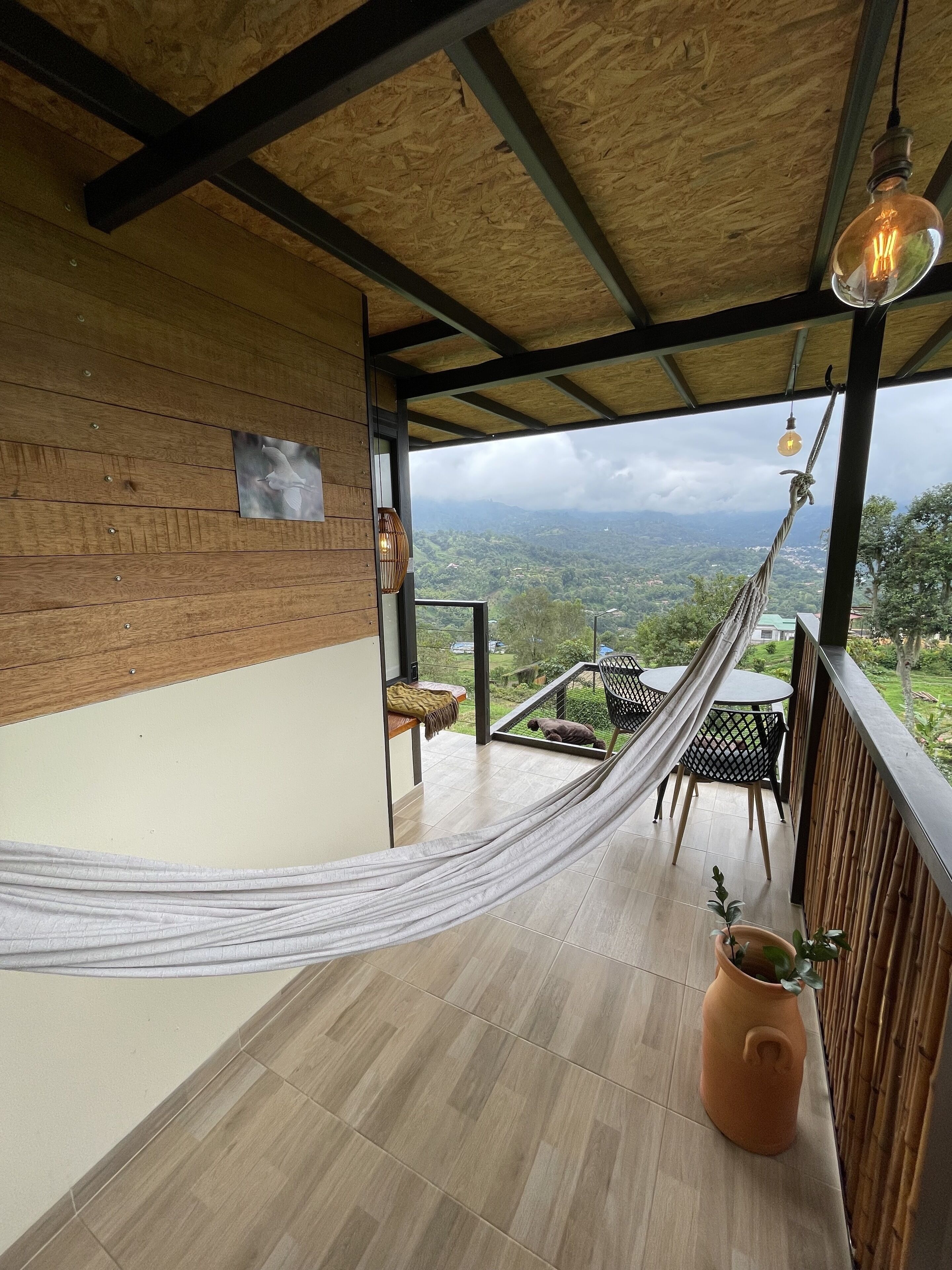 Uma rede numa varanda com vista para uma paisagem montanhosa.