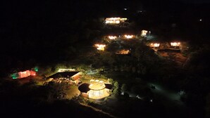 A nighttime view of a resort with multiple illuminated buildings, a central circular structure, and surrounding greenery. - Natubri Ecohotel (San Francisco)