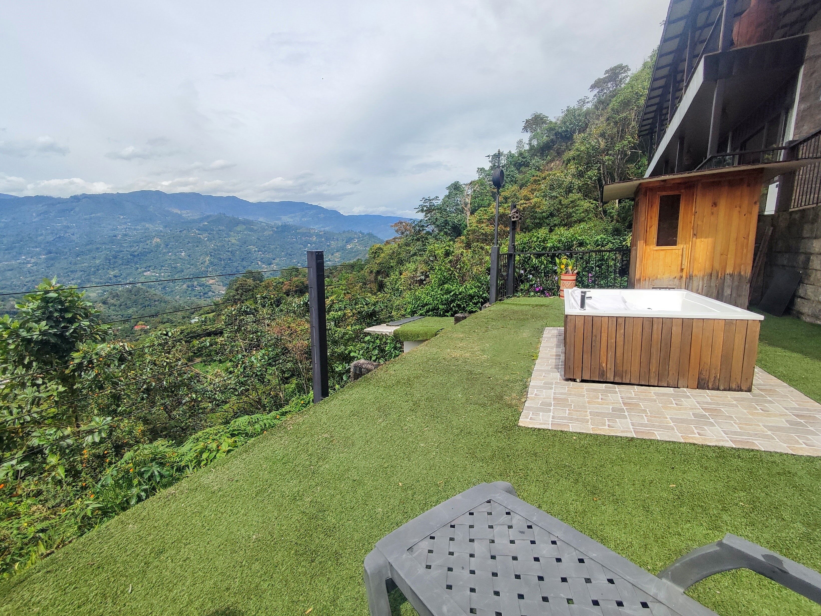 A patio area with a hot tub, a view of mountains, and a wooden cabin.