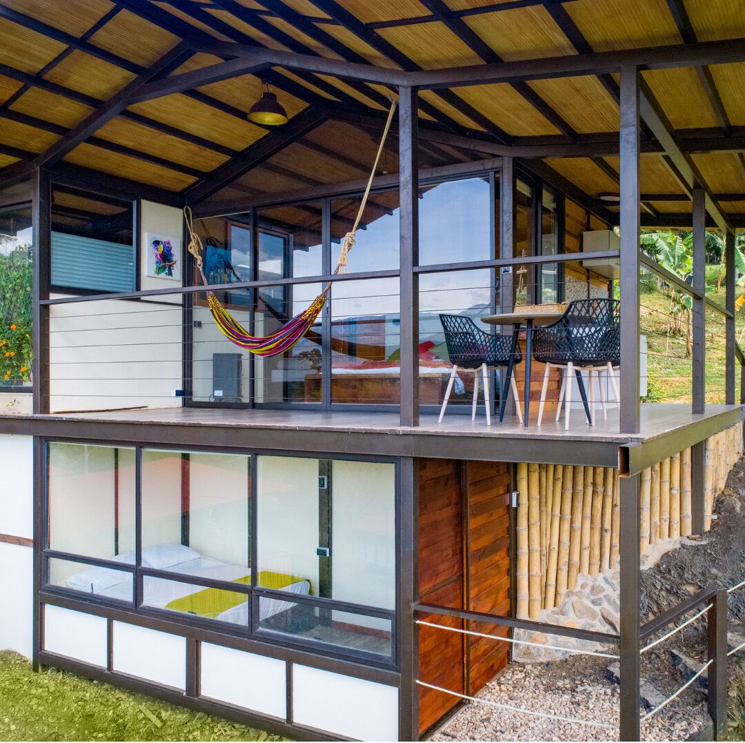 A modern house with a glass extension, a hammock, and outdoor seating.