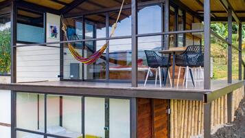 A modern house with a glass extension, a hammock, and outdoor seating.