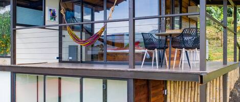 Una casa moderna con un porche de cristal, una hamaca y mobiliario de exterior.