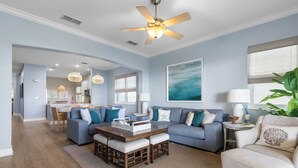 Un salon spacieux avec un canapé bleu, une table basse en bois et un ventilateur de plafond.