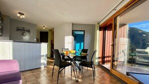 Een moderne keuken met een eethoek, een groot raam met uitzicht op de bergen, en een paarse stoel.