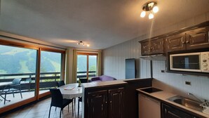 Een moderne keuken met donkere houten kastjes, een ingebouwde magnetron en een groot raam met uitzicht op een prachtig landschap.