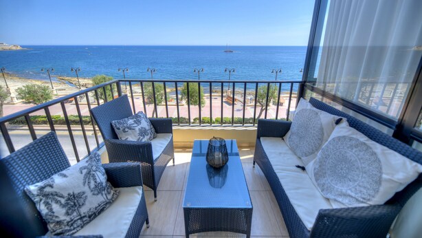 A balcony with wicker furniture, a glass table, and a view of the sea. - Seafront apartment in the heart of Sliema MMAI2 (Sliema)