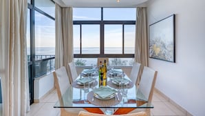 A dining area with a glass table, chairs, and a view of the sea. - Seafront apartment in the heart of Sliema MMAI2 (Sliema)