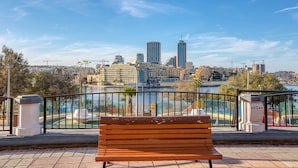 A bench overlooking a cityscape with a river, buildings, and a clear sky. - Seafront apartment in the heart of Sliema MMAI2 (Sliema)