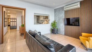 A modern living room with a leather sofa, a yellow armchair, a flat-screen TV, and a wooden panel wall. - Seafront apartment in the heart of Sliema MMAI2 (Sliema)