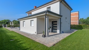 A modern two-story house with a covered patio, a stone facade, and a brick extension.