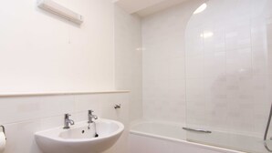 Un baño con lavamanos blanco, espejo y bañera.