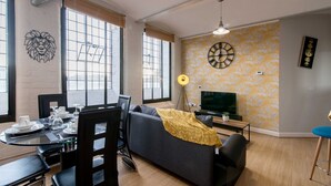 Un salon moderne comprenant un canapé, une table à manger, des chaises et un téléviseur.