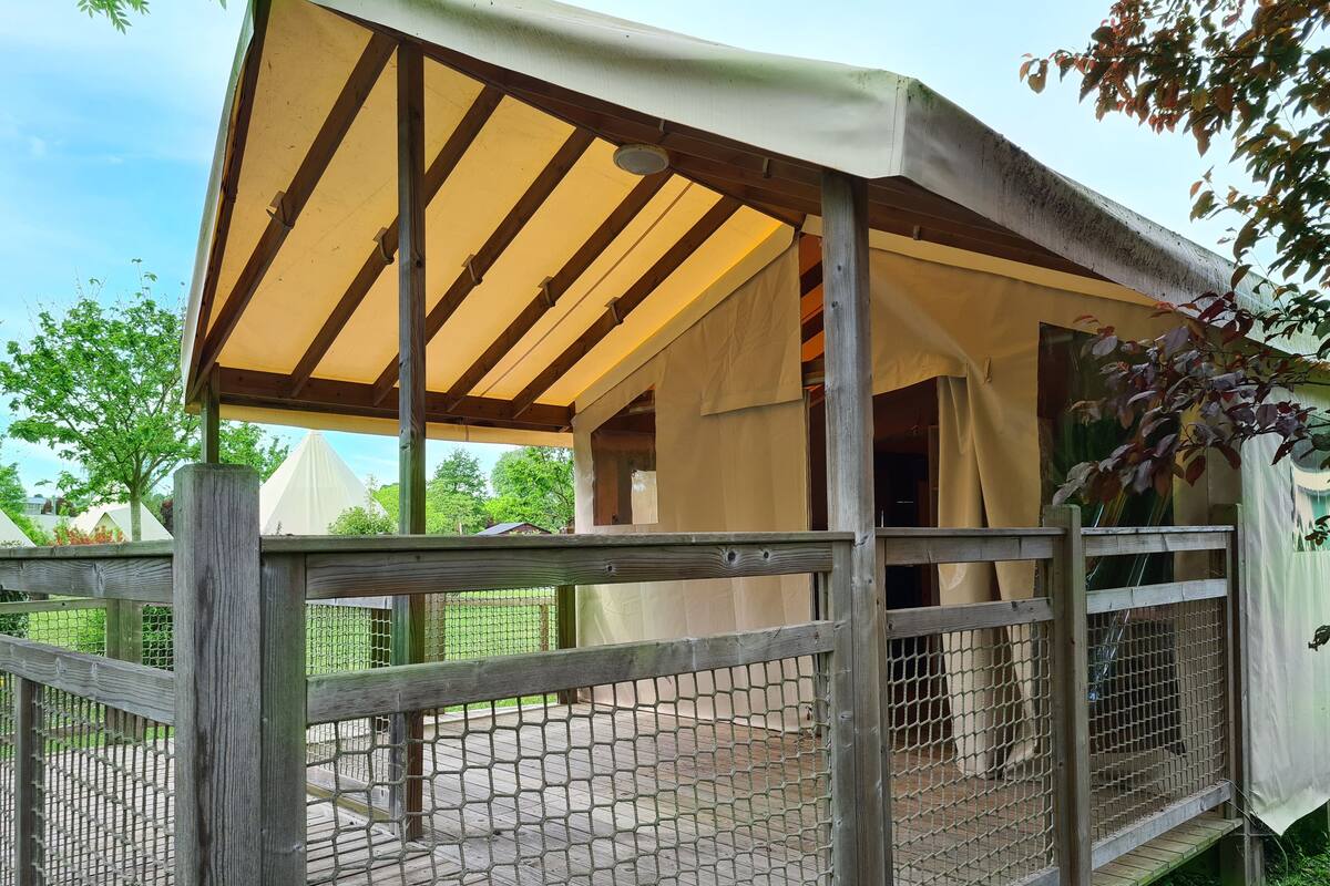 A wooden deck with a mesh fence and a covered area with a canopy.