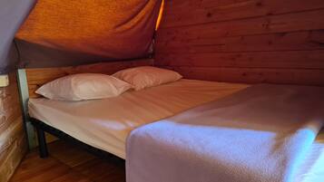 A single bed with white bedding in a wooden cabin-style room.