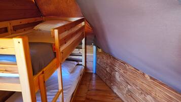 Ein Stockbett in einem Zimmer mit Holzwänden und einer geneigten Decke.