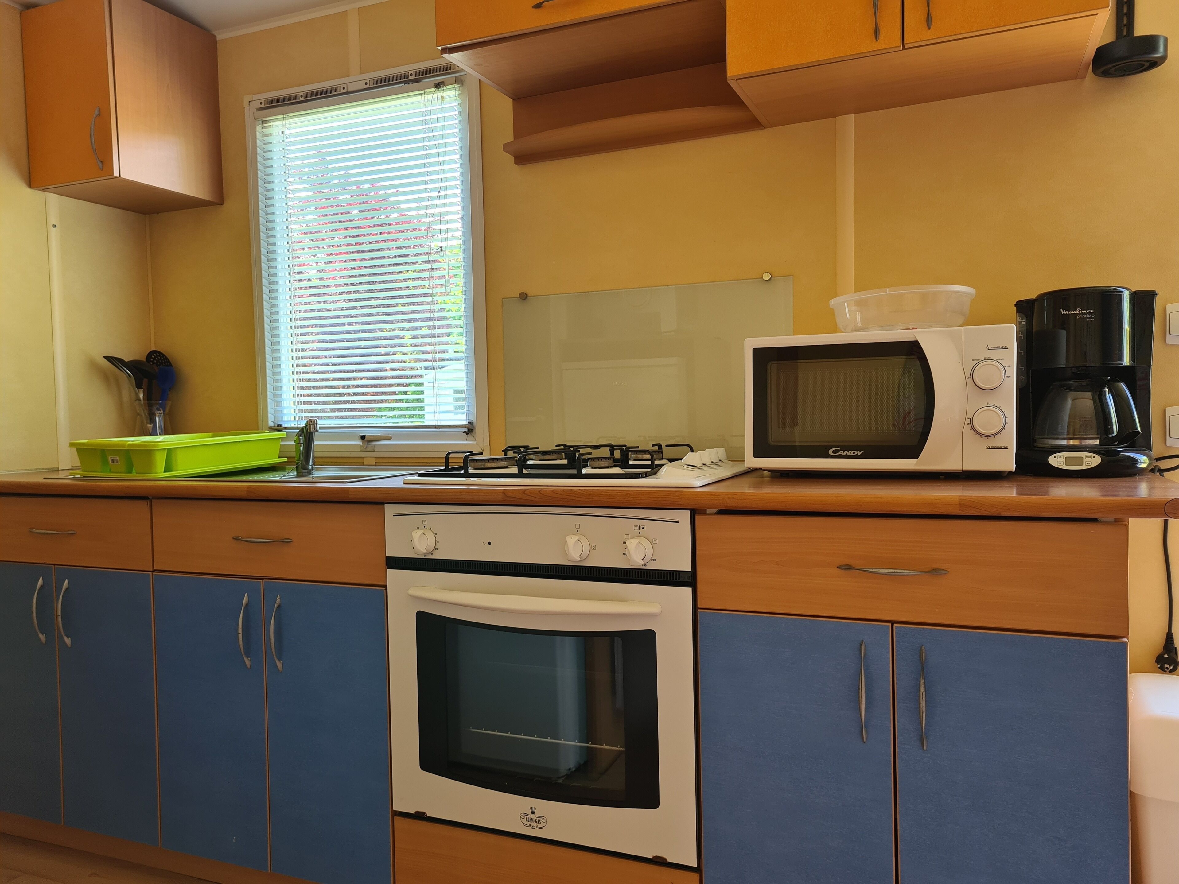 A kitchen with a gas stove, microwave, oven, and a coffee maker.