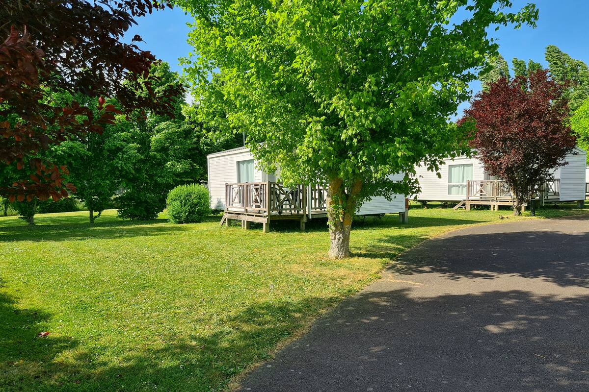 A grassy area with a paved path leading to mobile homes.