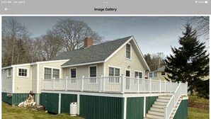 A two-story house with a covered deck and a staircase leading to the upper level. - All Aboard Cottage (East Boothbay)