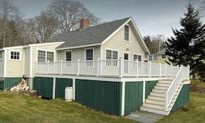 Une maison à deux étages dotée d’une terrasse couverte et d’un escalier menant à l’étage supérieur.