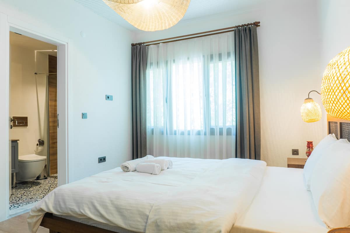 Habitación de hotel con cama, baño y ventana con cortinas.