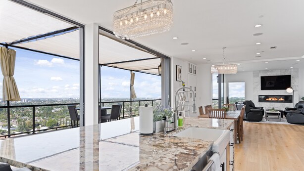 A modern kitchen with a large island, a dining area with a fireplace, and a view of the city. - 360° HILLTOP VIEW / Ultra Modern / 15min DISNEY (Santa Ana)