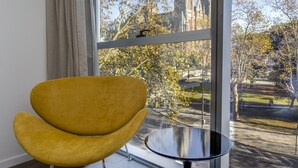 A modern room with a large window, a yellow chair, and a small round table.