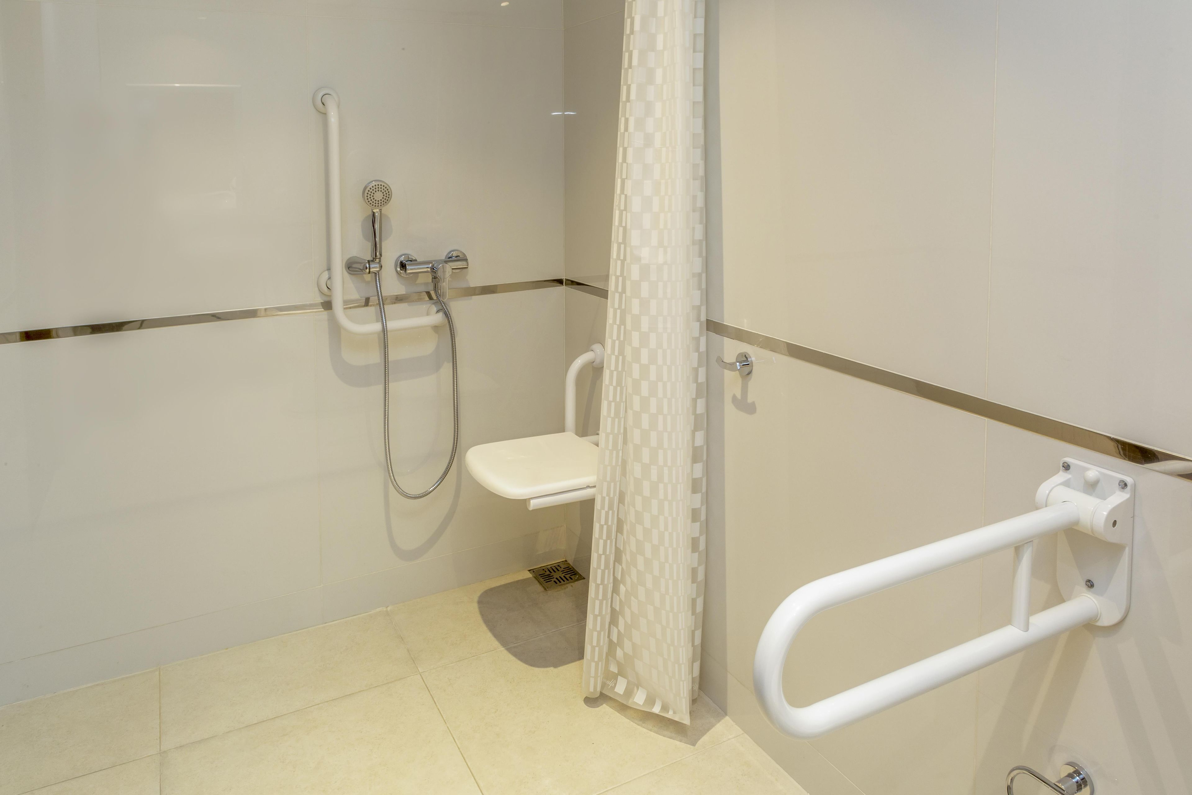Une salle de bain équipée d’une douche, de toilettes et d’une barre d’appui.