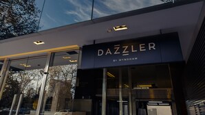 A modern building with a glass facade and a sign that reads "DAZZLER BY WYNDHAM".