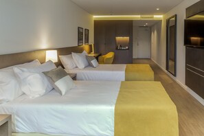 A hotel room with two beds, a sofa, a TV, and a desk with a lamp.