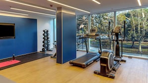 A modern gym with a treadmill, elliptical, and weight rack.