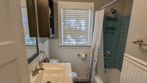 Une salle de bain équipée d’un lavabo, d’un miroir, d’une fenêtre, d’une douche et d’un porte-serviettes.