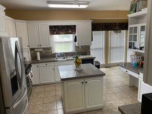 A kitchen with white cabinets, a granite countertop, and a stainless steel refrigerator.