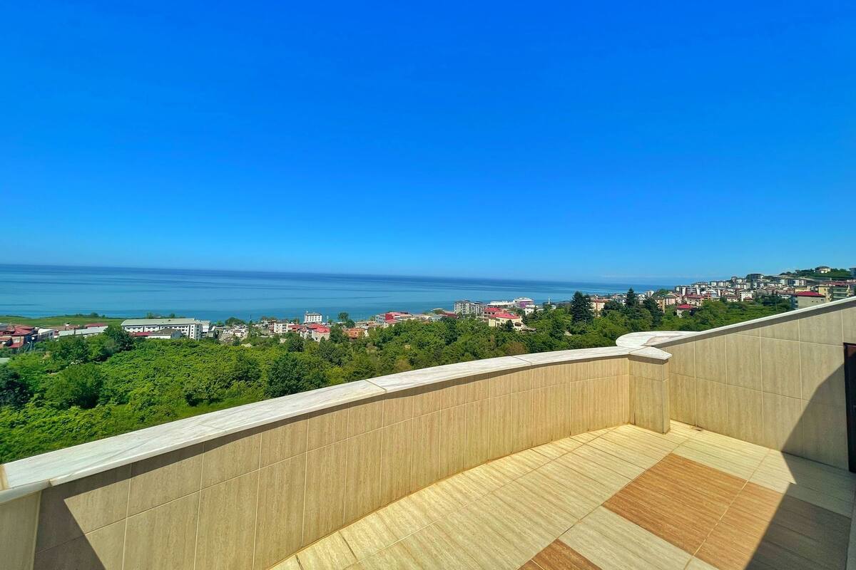 A balcony with a view of a coastal cityscape and the sea.
