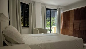 Een hotelkamer met een groot bed, een stoel en uitzicht op groen.