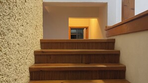 Een houten trap met een gestructureerde muur aan de ene kant en een raam aan de andere kant.