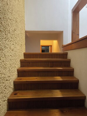 Eine Holztreppe mit einer strukturierten Wand und einem Fenster auf der anderen Seite.