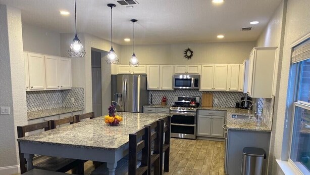 A modern kitchen with granite countertops, stainless steel appliances, and a central island with seating.