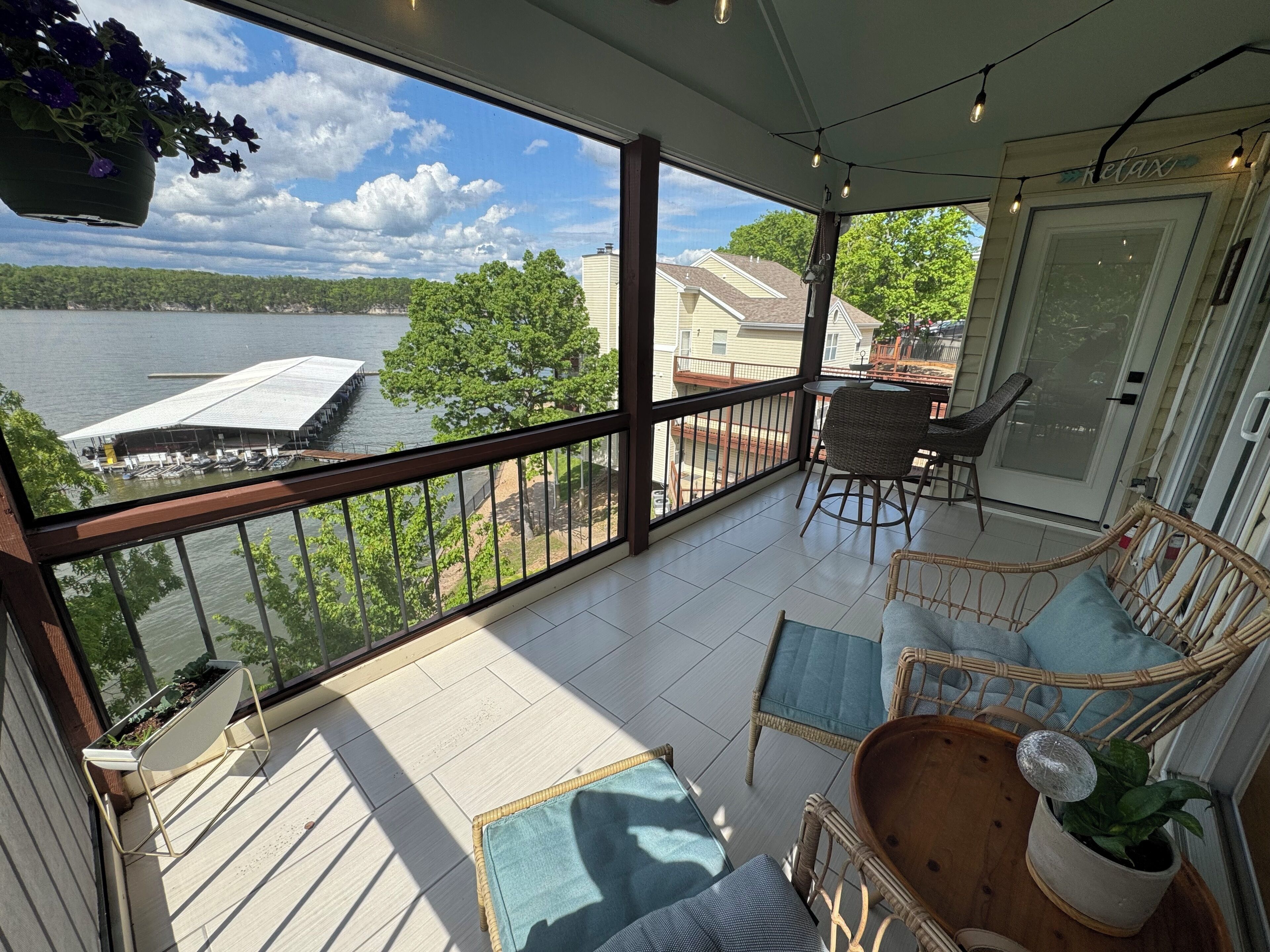 Ein Balkon mit Seeblick, Korbmöbeln und einer Tür mit der Aufschrift 'Relax'.