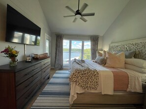 Une chambre à coucher avec un lit, une commode, un téléviseur et une vue sur l’extérieur.