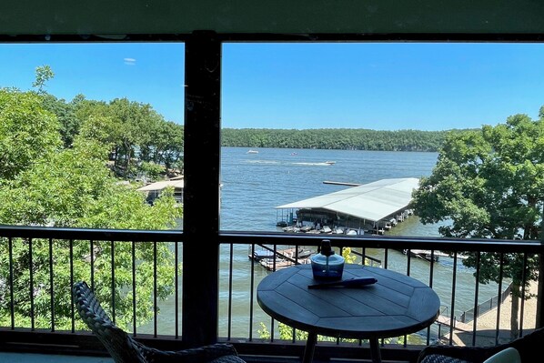 Un balcon avec vue sur un lac, une jetée et un bâtiment situé de l’autre côté de l’eau.