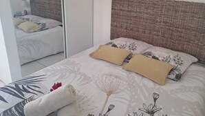 Un dormitorio con un espejo grande, una cama con ropa de cama floral y un cabecero de mimbre.