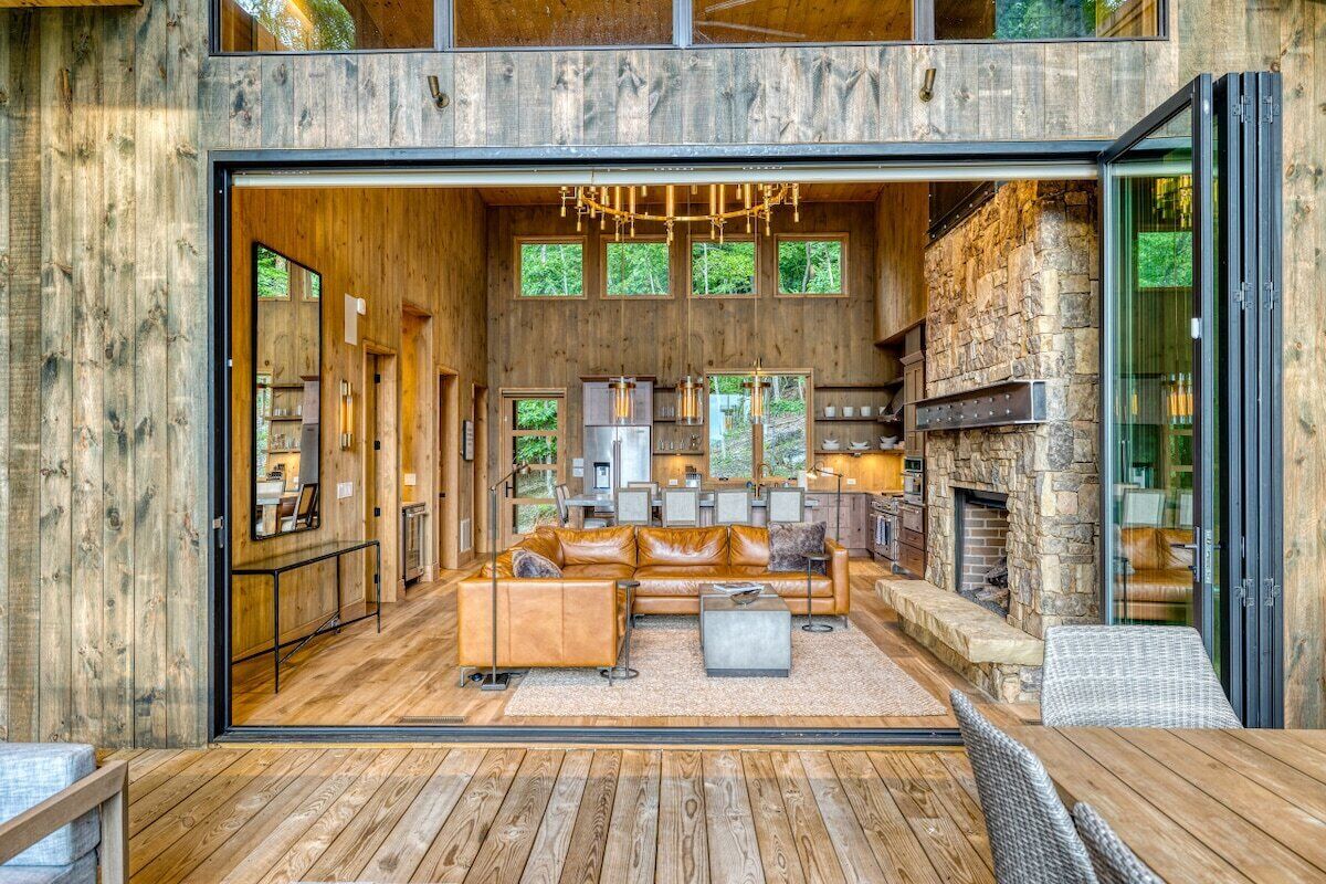 An open-plan living area with a fireplace, wooden flooring, and a view of the outdoors.